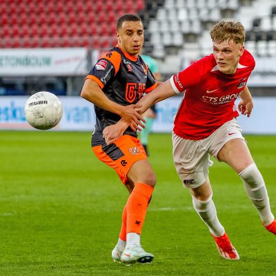 Jong AZ heeft maandagavond in het AFAS Stadion met 0-1 verloren van FC Volendam. In een open wedstrijd met kansen over en weer trokken de Volendammers uiteindelijk aan het langste eind. Door de zege stelde de ploeg van Rick Kruys directe promotie naar de Eredivisie veilig. Jong AZ zakt door de nederlaag één plek en staat nu dertiende in de Keuken Kampioen Divisie. De ploeg van Lee-Roy Echteld blijft ondanks het verlies wel het best presterende beloftenteam. Aanstaande vrijdag wacht een uitwedstrijd tegen nummer zeven FC Emmen, in De Oude Meerdijk.
Vier wijzigingen bij Jong AZ
Trainer Lee-Roy Echteld, terug na een schorsing, wijzigde zijn basiself op vier posities ten opzichte van het duel met Jong PSV. Sem Westerveld verving Hobie Verhulst onder de lat. Daarnaast kregen Kasper Boogaard, Julian Oerip en Yoël van den Ban een basisplaats. Nick Twisk, Kees Smit en Mexx Meerdink begonnen daardoor op de bank.
Open eerste helft met kansen over en weer
Volendam had bij winst promotie naar de Eredivisie in eigen hand en startte fel. Binnen twee minuten kreeg de ploeg van Rick Kruys al twee grote kansen. Oud-AZ’er Robert Mühren testte doelman Sem Westerveld, die knap redde. Uit de daaropvolgende hoekschop kopte Xavier Mbuyamba over. Aan de andere kant was Jayden Addai dicht bij een treffer, maar zijn schot werd geblokt, en even later schoot hij hoog over. Volendam bleef gevaarlijk en trof in de eerste helft meerdere keren het houtwerk. Henk Veerman kopte op de paal, en Bilal Ould-Chikh schoot uit een vrije trap op de lat. Tien minuten voor rust moest topscorer Ro-Zangelo Daal geblesseerd naar de kant; hij werd vervangen door Sem van Duijn. Kort voor rust was Veerman opnieuw dicht bij de openingstreffer, maar zijn krul ging over. In blessuretijd kreeg Jong AZ via Kasper Boogaard nog een kans, maar doelman Van Oevelen redde knap. Met 0-0 zochten beide teams de kleedkamer op.
Plat bezorgt Volendam promotie
Vlak na rust werd Jong AZ gevaarlijk via Addai, maar Van Oevelen redde opnieuw. Aan de overkant mikte Alex Plat nog over, maar halverwege de tweede helft was het wel raak. De middenvelder schoot de bal vanaf de rand van het zestienmetergebied langs Westerveld: 0-1. Jong AZ probeerde via schoten van Oerip, Addai en Boogaard nog iets terug te doen, maar tot een goal kwam het niet. Grote kansen bleven in de slotfase uit, waardoor FC Volendam de promotie definitief veiligstelde.
Komende vrijdag: uit naar FC Emmen
Door de nederlaag zakt Jong AZ naar de dertiende plek. Toch blijft de ploeg het hoogst geklasseerde beloftenteam in de competitie. Vrijdag wacht in Emmen een nieuwe uitdaging: de nummer zeven van de ranglijst is dan de tegenstander. Foto: PRO SHOTS / Vincent de Vries